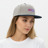 Woman wearing heather grey and navy snapback, head tilted down